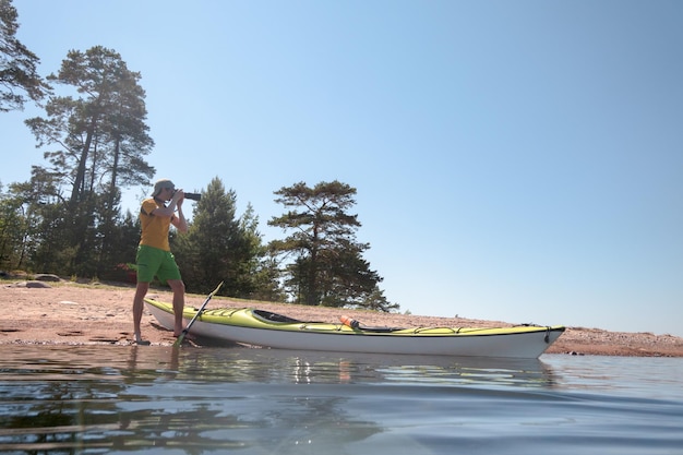 Fotógrafo naturalista trabajando en la orilla en un lugar pintoresco Junto a él hay un kayak