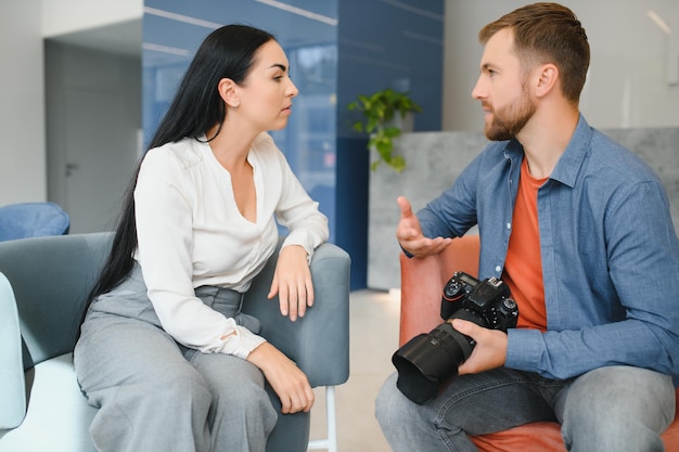 Fotógrafo no escritório mostra modelo de foto na câmera Consultor ajusta as atividades da empresa como um todo Sessão de fotos funcionários no local de trabalho Gerente projeto bem executado Fotos melhores funcionários da empresa