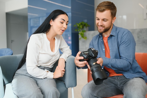 El fotógrafo en la oficina muestra un modelo de fotografía en la cámara. El consultor ajusta las actividades de la empresa en su conjunto. Sesión de fotos de los empleados en el lugar de trabajo.