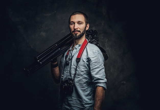 Foto el fotógrafo pensativo sostiene una lámpara especial para un set de fotos en un estudio fotográfico oscuro.