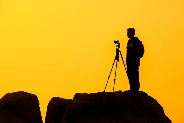 Fotógrafo de pie en una roca al atardecer