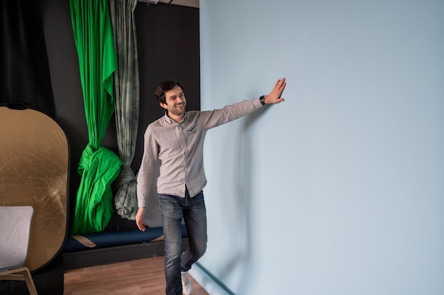 Fotógrafo se prepara para disparar en un estudio fotográfico. Hombre cambiando el fondo de papel en un estudio fotográfico