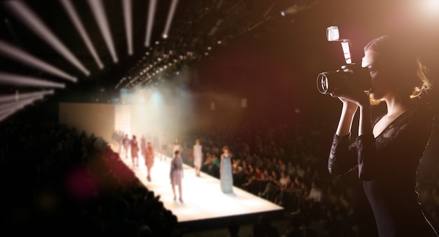 Fotógrafo press woman usa câmera para tirar fotos do desfile da fashion week em que modelo supermodelo anda na passarela para nova coleção de marca de grife, espaço de cópia de plano de fundo