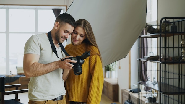 Fotógrafo profesional que muestra fotos en una cámara digital a una hermosa modelo