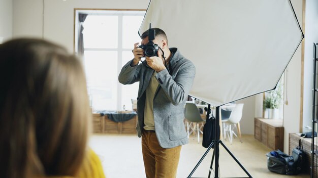 Fotógrafo profesional tomando fotos de modelo en cámara digital trabajando en estudio fotográfico