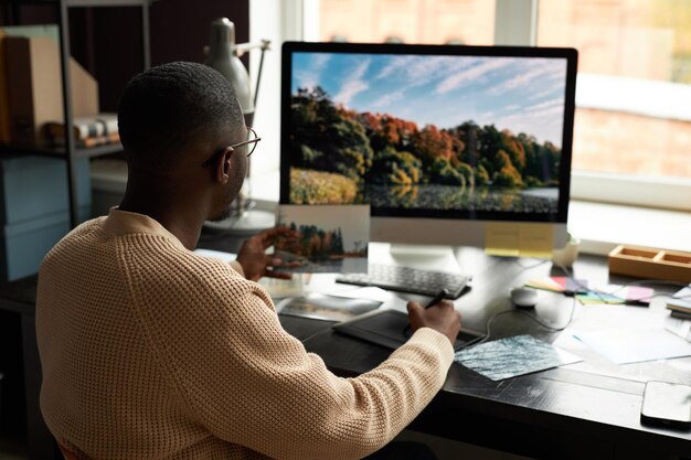 Fotógrafo profissional editando fotos no computador na mesa em seu escritório doméstico