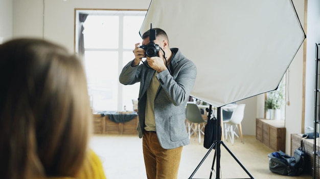 Fotógrafo profissional tirando fotos de modelo na câmera digital trabalhando em estúdio fotográfico