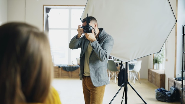 Fotógrafo profissional tirando fotos de modelo na câmera digital trabalhando em estúdio fotográfico