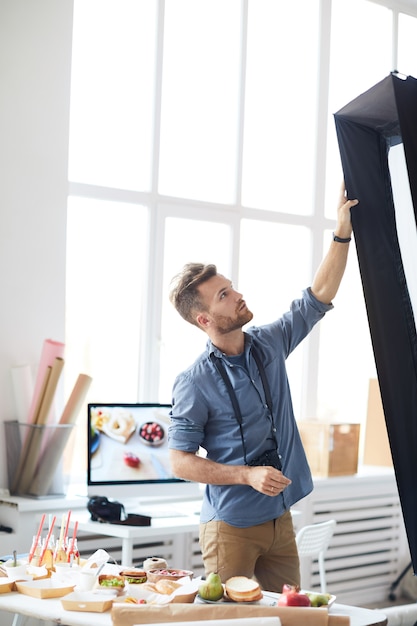 Fotógrafo que ajusta o equipamento leve no estúdio