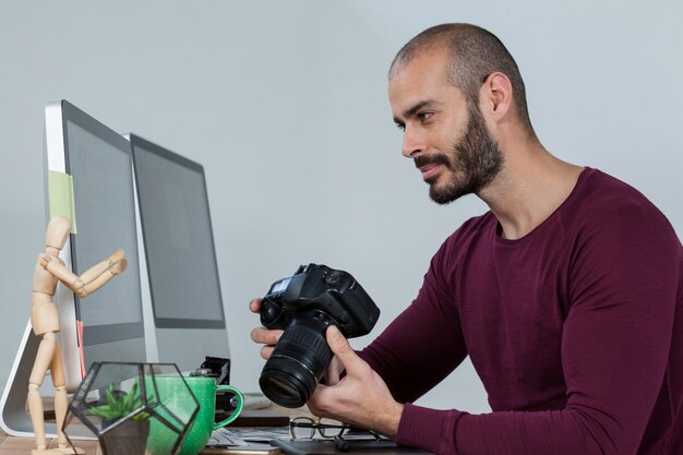 Foto fotógrafo sentado na mesa, segurando a câmera