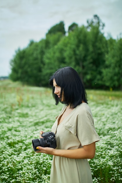 Fotógrafo de sexo femenino toma la foto al aire libre en el paisaje del campo de flor que sostiene una cámara, la mujer sostiene la cámara digital en sus manos. Fotografía de naturaleza de viajes, espacio para texto, vista superior.