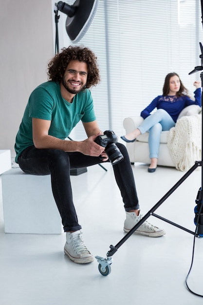 Fotógrafo sorridente, sentado no estúdio com a câmera