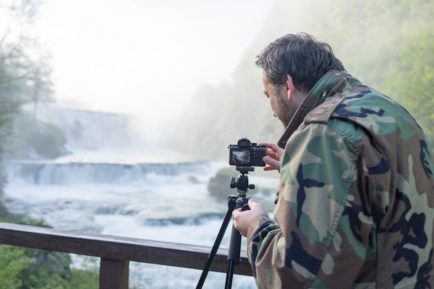 Fotógrafo tirando foto de cachoeira no início da manhã