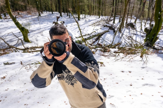 Fotógrafo tirando uma foto na neve curtindo a fotografia de inverno em uma floresta de faias