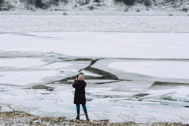 El fotógrafo toma fotografías de hielo transparente congelado en el río de invierno.