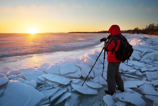 Fotógrafo toma fotografías en la orilla del río en invierno