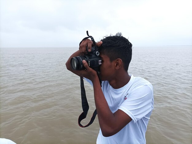 Foto un fotógrafo tomando una foto con una cámara dslr en un día lluvioso en el fondo del océano fotógrafo en la playa temprano en la mañana en un día nublado antes del amanecer