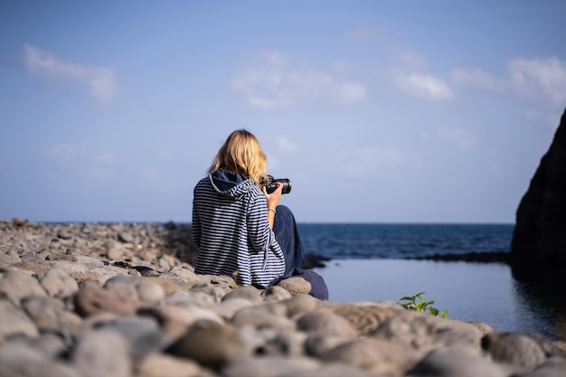 Fotógrafo tomando fotos del mar con una cámara digital desde una playa