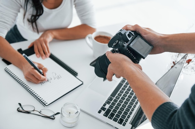 Fotógrafo en el trabajo Dos jóvenes mujeres independientes en el interior de la oficina durante el día