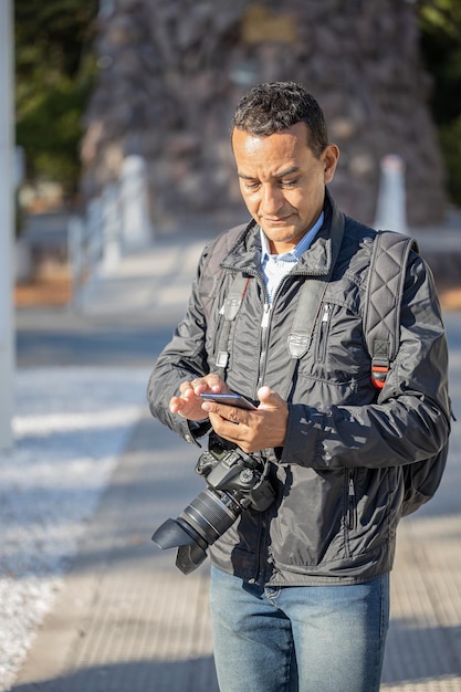 Fotógrafo trabalhando na rua e enviando mensagens de texto com seu celular