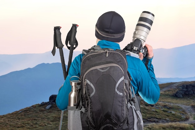 fotógrafo turístico masculino con una mochila mira la belleza de la naturaleza en las montañas