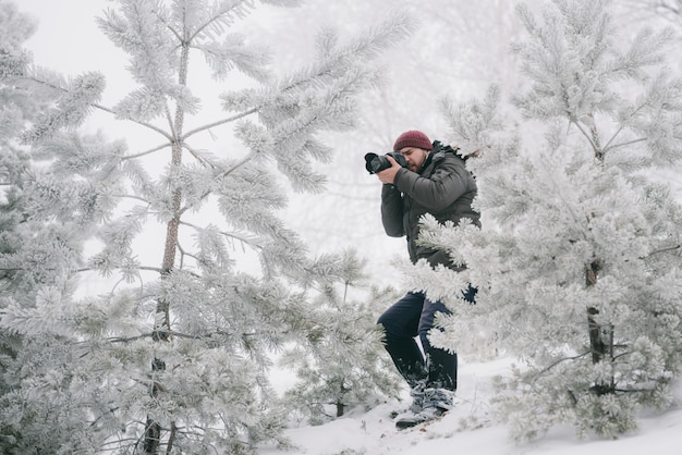 Fotógrafo viajero tomando fotos en el bosque de invierno