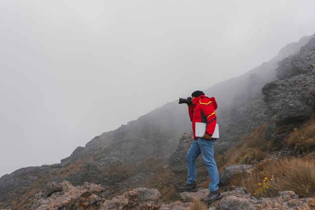 Fotógrafo de viajes con cámara y portátil en las montañas