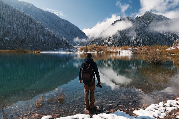 Fotógrafo de viajes hombre con mochila en el lago de montaña Issyk Almaty Kazajstán