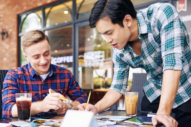 Fotógrafos discutindo fotos impressas em um café ao ar livre