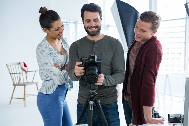 Fotógrafos e modelo revendo fotos capturadas em sua câmera digital