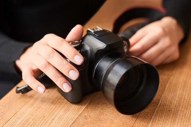 Fotokamera in der Hand auf Holztisch im internationalen Fotografentag