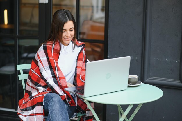 Fotoporträt einer wunderschönen attraktiven Frau, die am Laptop arbeitet und im Café Kaffee trinkt