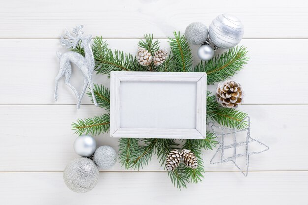 Fotorahmen mit Weihnachtsdekoration, mit weißen Bällen und Kiefernkegeln auf einem weißen Holztisch. Draufsicht, Feld, zum des Raumes zu kopieren