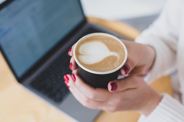 Fotos de mãos de mulheres segurando um copo de papel com café.