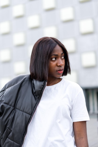 Fotos de estilo de vida de verano de una joven negra con gafas de sol y sombrero con una camisa verde en una pared marrón