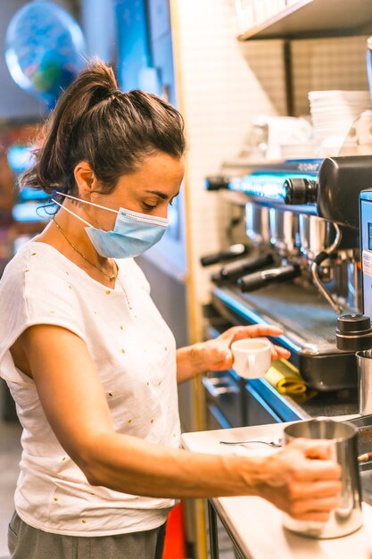 Fotosession mit einer Kellnerin mit einer Gesichtsmaske in einer Bar. Kaffeeschnitt vorbereiten