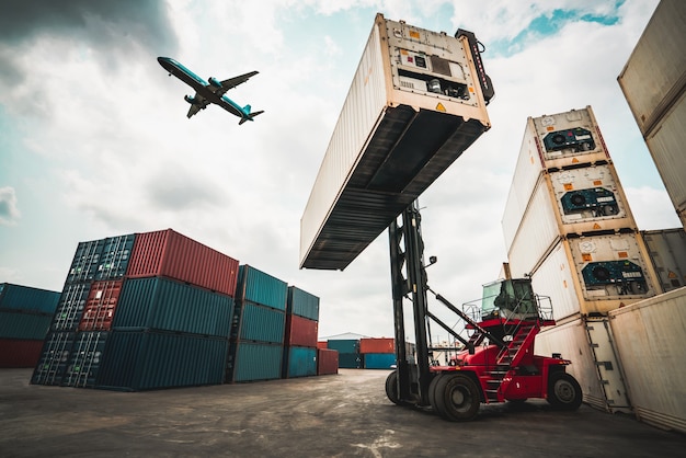 Frachtcontainer für den Überseeversand in der Werft mit Flugzeug am Himmel.