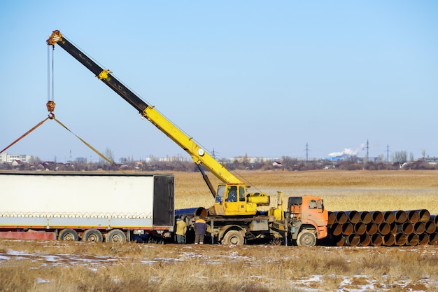 Frachttransport auf der Straße auf der ganzen Welt Beladen eines Lastwagens mit einem Pipeline-Kran Russland