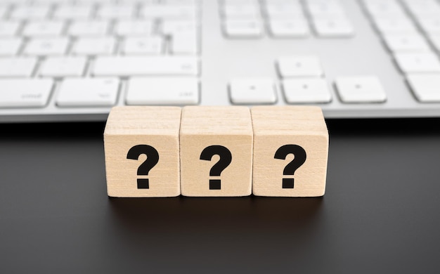 Fragen Markierung auf Holzblock und Computer-Tastatur FAQ Antwort