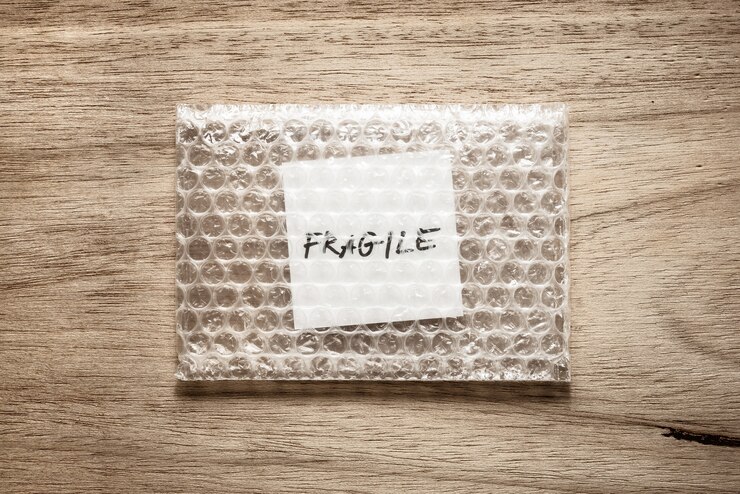 frágil, caligrafia em papel quadrado branco no pacote de bolha