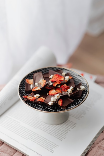 Frágil chocolate oscuro con fresa seca en un plato en un libro abierto