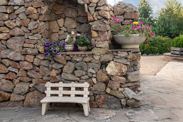 Fragment der Landschaftsgestaltung des Parks. Steinmauer, Bank, Topfblumen.