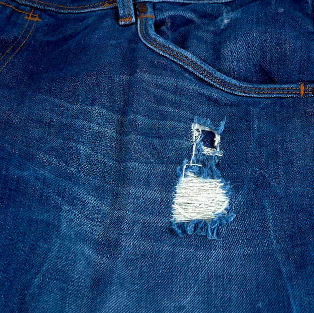 Fragment des Blue Jeansgewebes mit einem Loch