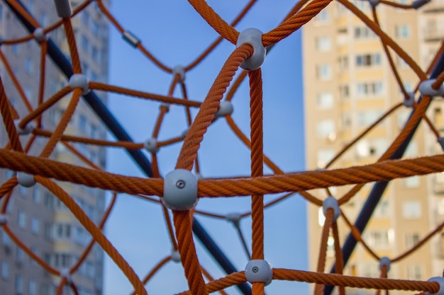 Fragment des Spinnennetzes auf dem Spielplatz Detail überqueren Sie orangefarbene Seile in Sicherheitskletterausrüstung für den Außenbereich