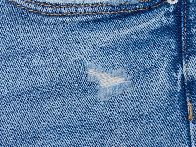 Fragment von Blaue Jeans Stoff mit einem Loch vollen Rahmen in der Nähe