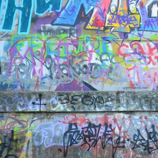 Fragment von Graffiti-Tags Die alte Mauer ist mit Farbflecken im Stil der Street-Art-Kultur verwöhnt