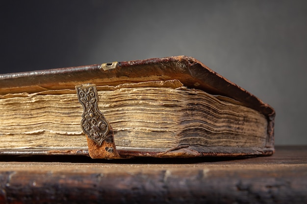 Un fragmento de un antiguo libro marrón con broches y páginas amarillas sobre una vieja mesa de madera