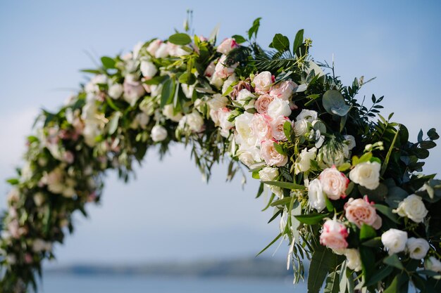 Fragmento de un arco de boda decorado con rosas de té blanco y rosa y follaje verde