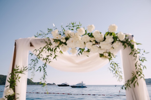 Fragmento de un arco de boda decorado con tul blanco y flores.