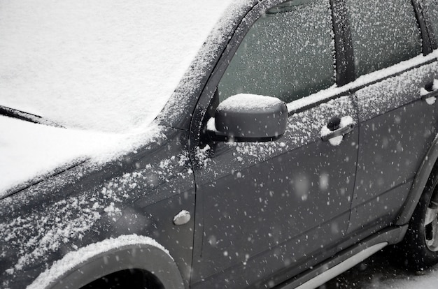 Fragmento del automóvil bajo una capa de nieve después de una fuerte nevada. El cuerpo del coche está cubierto de nieve blanca.